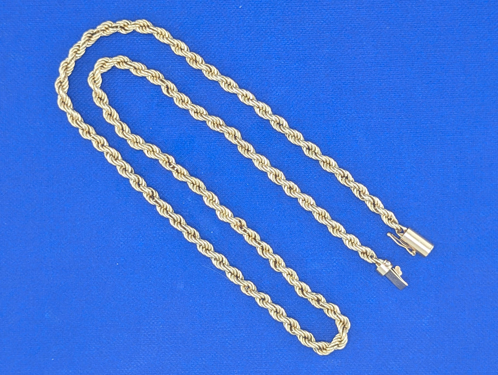 Gold rope chain necklace on a blue background